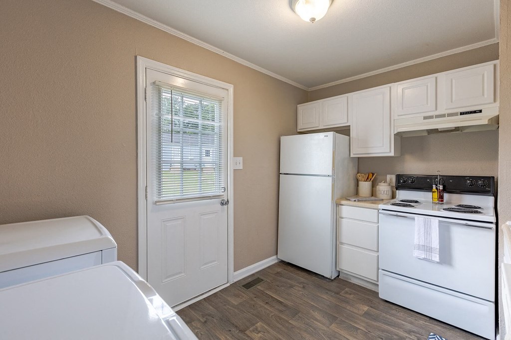 A kitchen with white appliances and wooden floors.
