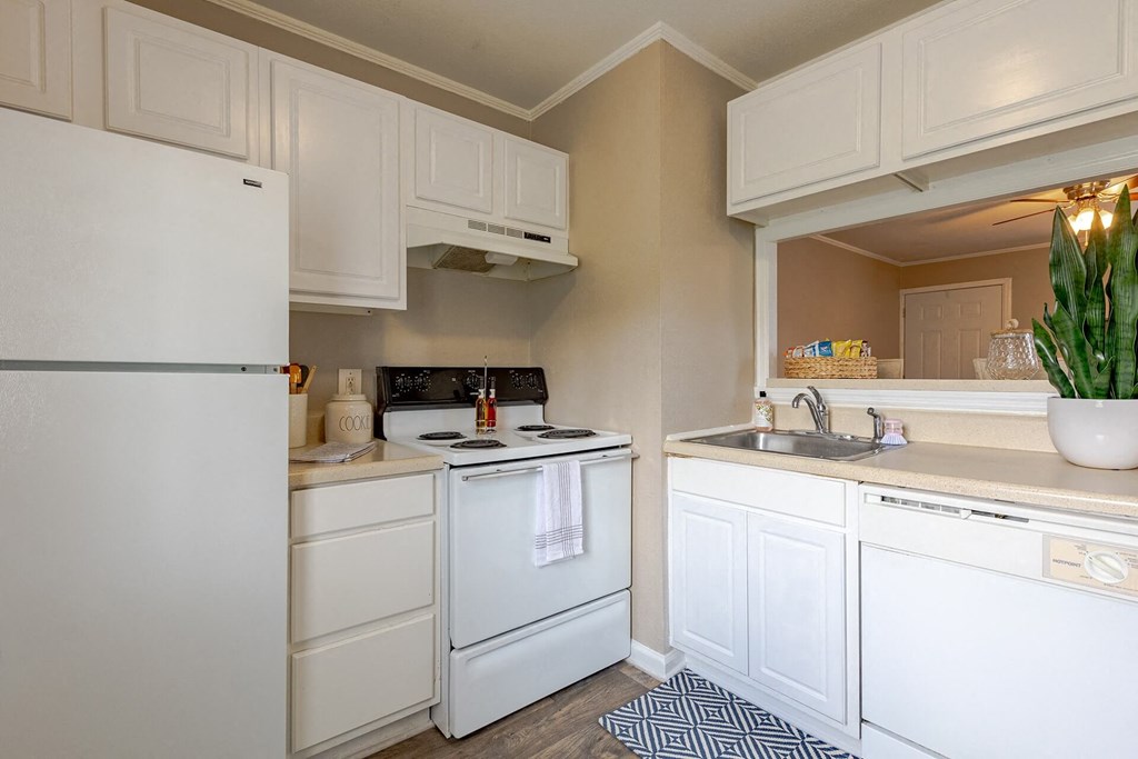A white refrigerator is in a kitchen with white cabinets.