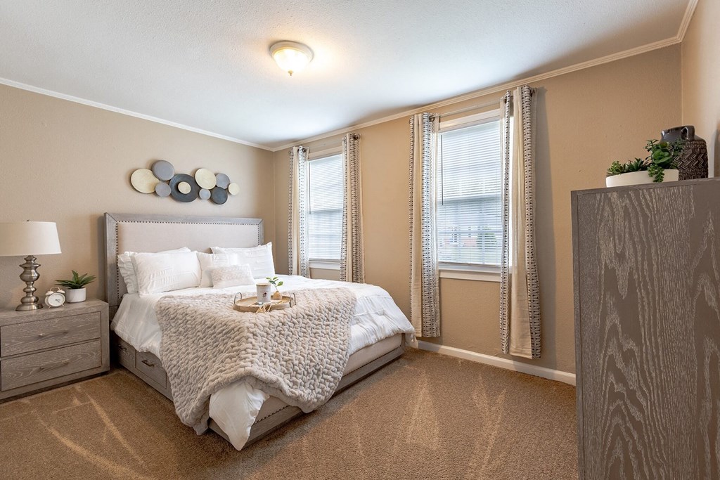 A bedroom with a large bed and a nightstand with a lamp.