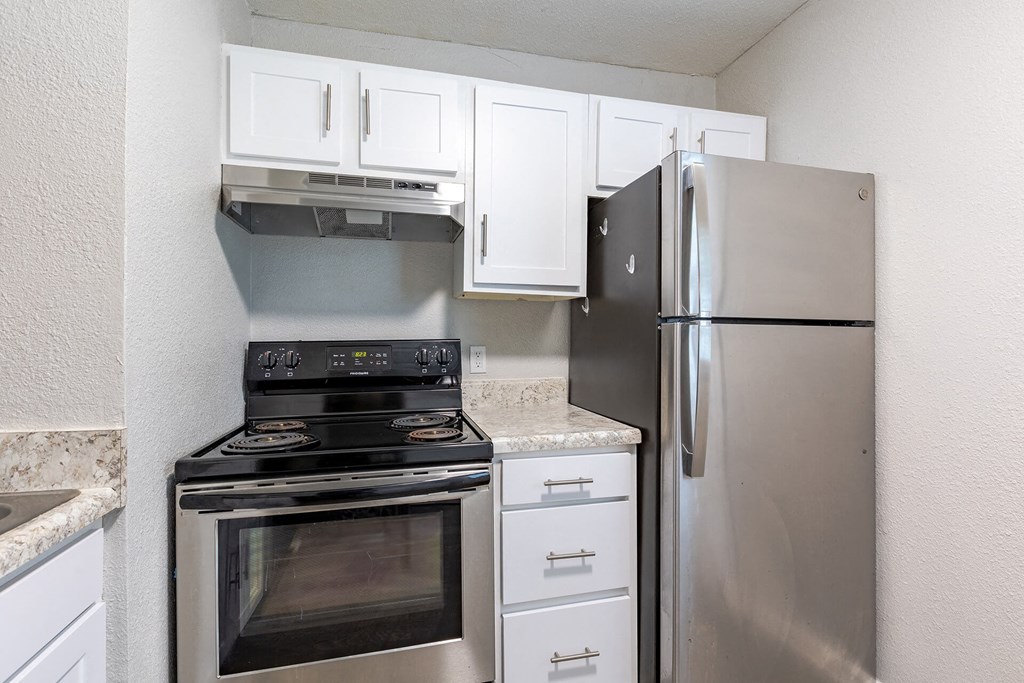A kitchen with a stove, refrigerator, and cabinets.
