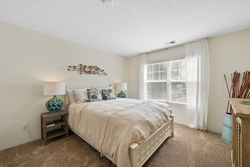 A bedroom with a large bed and a wooden nightstand.
