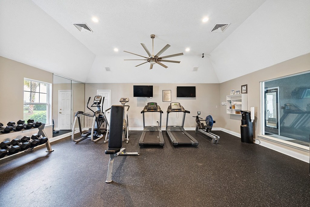 A spacious home gym with a variety of equipment including a treadmill, stationary bike, and weight bench.