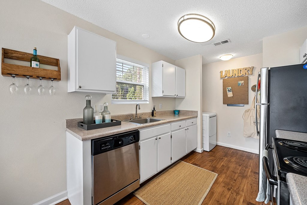 A small, clean, and well-equipped kitchen with white cabinets and stainless steel appliances.