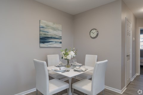 A dining room with a white table and chairs.