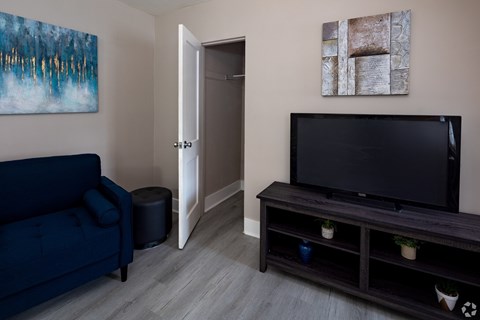 A living room with a blue couch, a television, and a painting on the wall.