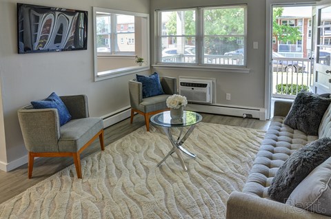 A living room with a grey couch, a coffee table, and a painting on the wall.