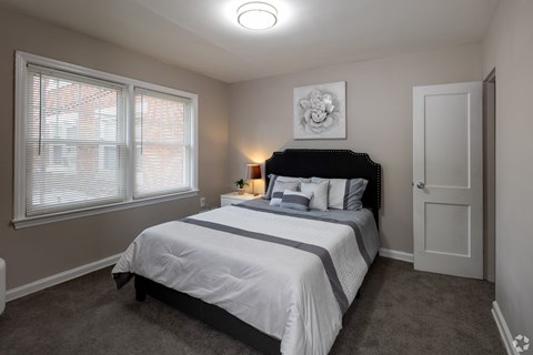 A bedroom with a bed, nightstand, and window.