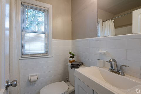 A white bathroom with a toilet, sink, and window.