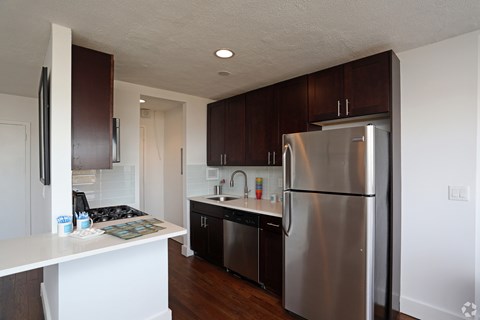 A kitchen with a stainless steel refrigerator and wooden cabinets.