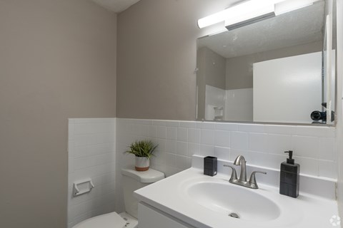 A white bathroom with a toilet, sink, and mirror.