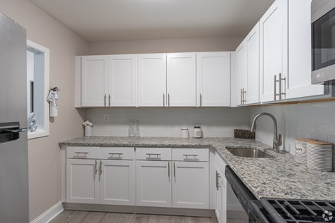 A kitchen with white cabinets and granite countertops.