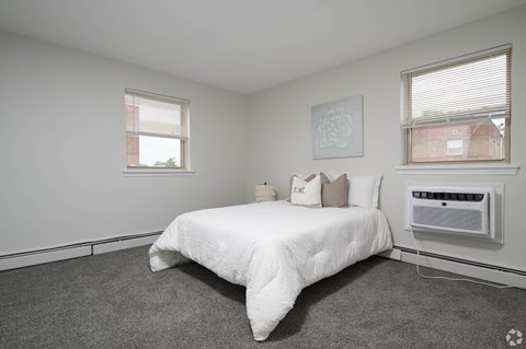 A bedroom with a bed, window, and air conditioner.