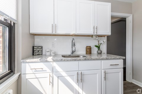 A kitchen with white cabinets and a marble countertop.