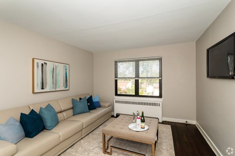A living room with a beige couch, a coffee table, and a painting on the wall.