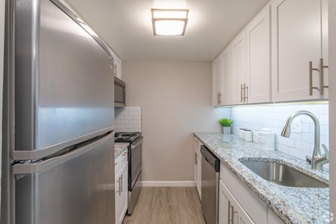 A kitchen with a stainless steel refrigerator and a granite countertop.