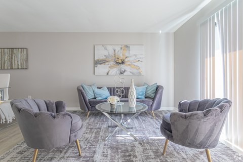 A living room with grey chairs and a glass table.