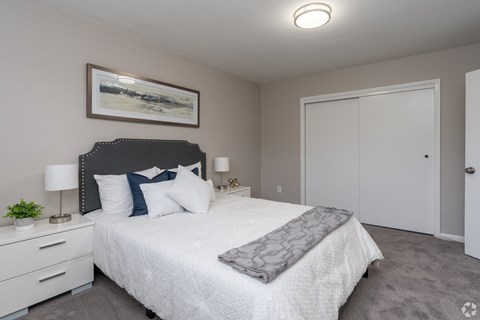 A bedroom with a large bed and a painting on the wall.