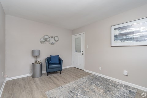 A room with a blue chair and a grey floor lamp.