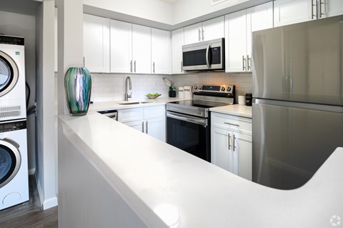 A modern kitchen with white cabinets and stainless steel appliances.