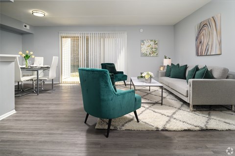 A living room with a green chair in the foreground and a dining area in the background.