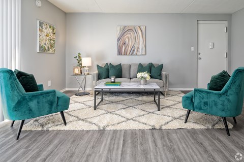 A living room with a grey couch, two green chairs and a coffee table.