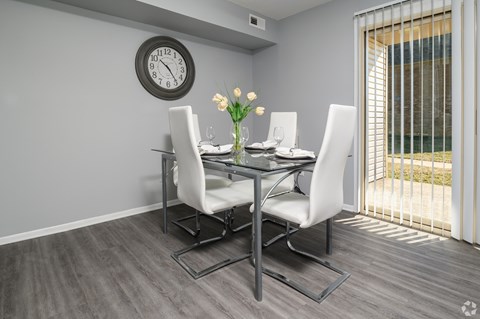 A dining table with four chairs and a clock on the wall.