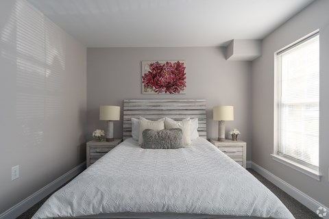 A bedroom with a large bed and two lamps.