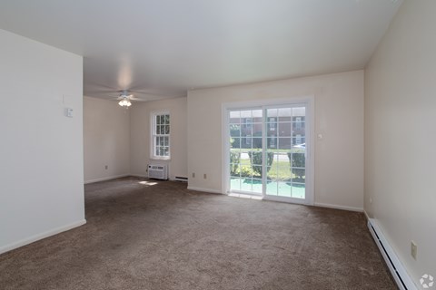 A spacious room with a carpeted floor and a ceiling fan.