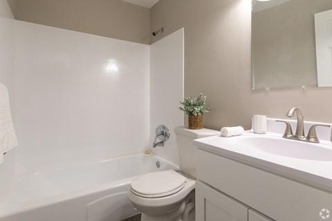 A white toilet sits next to a white sink in a small bathroom.