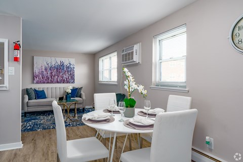 A dining room with a white table set for two.