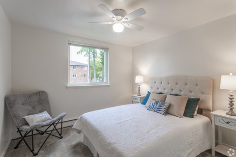 A bedroom with a white bed and a chair.