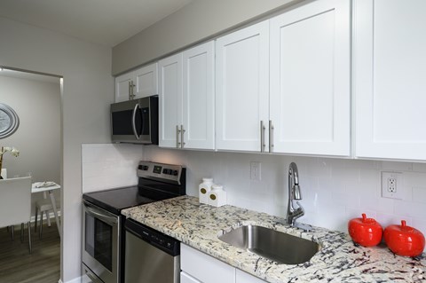 A kitchen with white cabinets and a granite countertop.