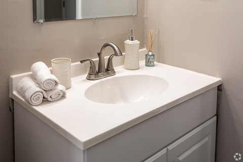 A white bathroom sink with a silver faucet and towels.