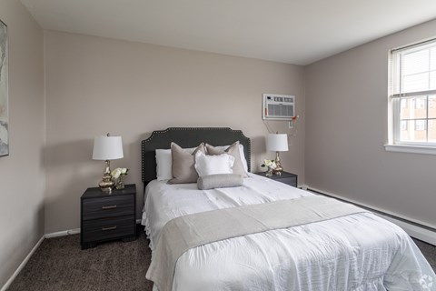 A bedroom with a large bed and two nightstands with lamps.