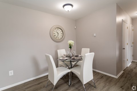 A dining room with a table set for two and a clock on the wall.
