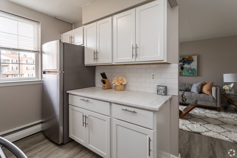 A kitchen with white cabinets and a stainless steel refrigerator.