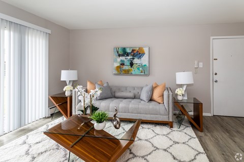 A modern living room with a grey couch, a wooden coffee table, and a painting on the wall.