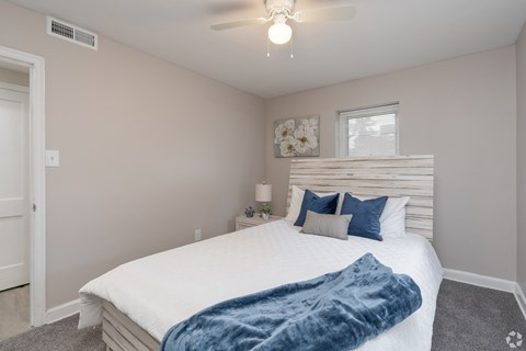 A bedroom with a bed, pillows, and a ceiling fan.