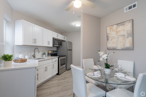 A modern kitchen with a glass dining table set for four.