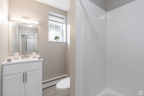A white bathroom with a toilet, sink, and mirror.
