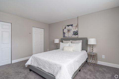 A bedroom with a large bed and two lamps.