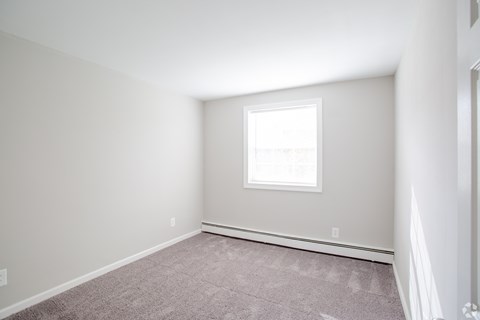 A room with a window and carpeted floor.