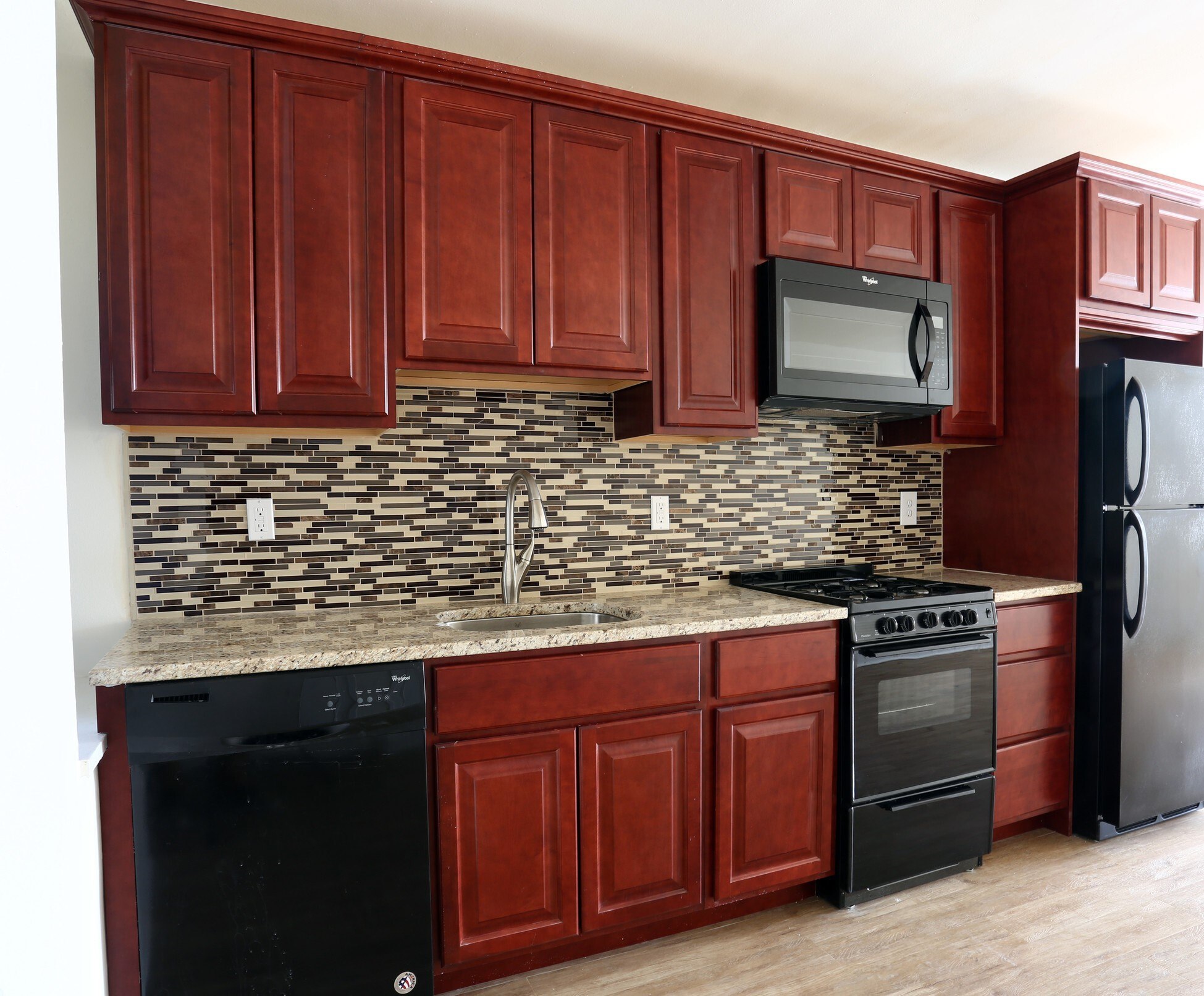 A kitchen with dark wood cabinets and black appliances.