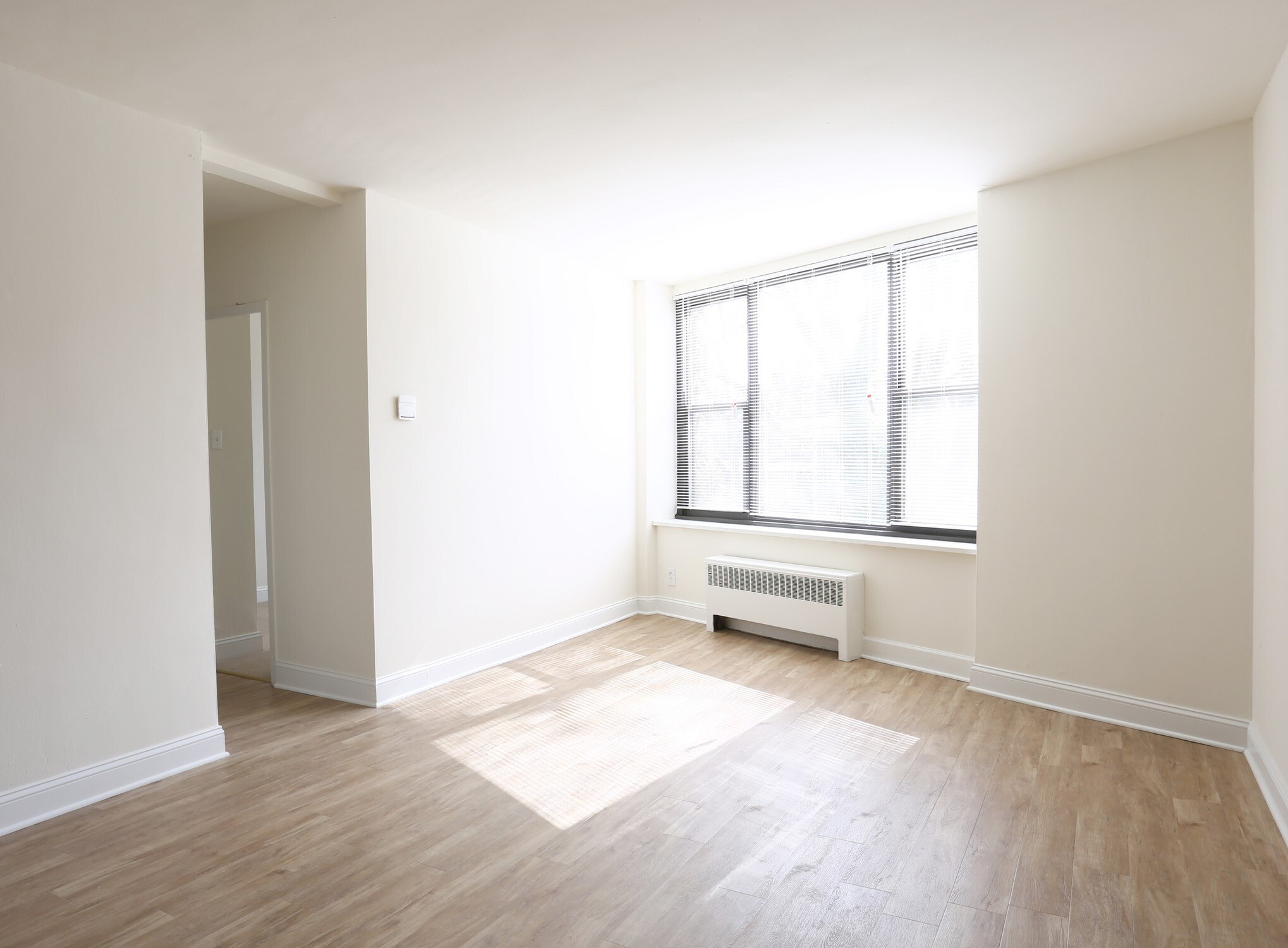 A room with a window and a radiator on the floor.