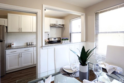 A kitchen with white cabinets and a dining table set for two.
