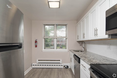 A kitchen with a stainless steel refrigerator and white cabinets.