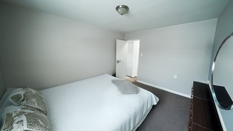 A bedroom with a bed, nightstand, and mirror.