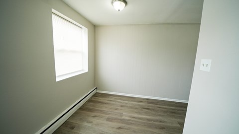 A room with a window and wooden flooring.