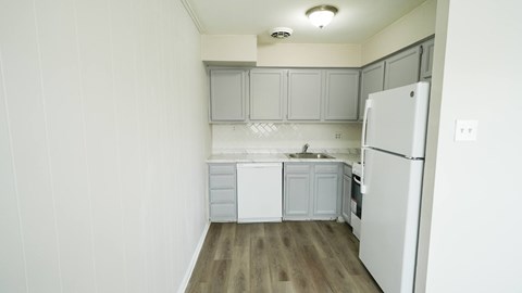 A white kitchen with a refrigerator, sink, and cabinets.