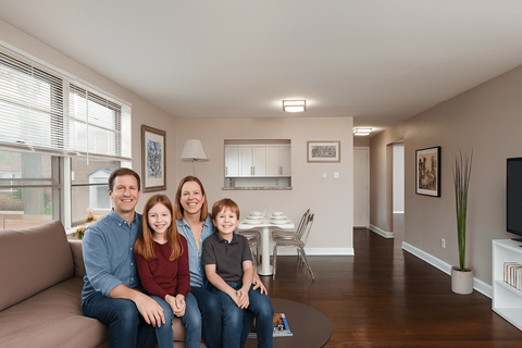 A family of four is sitting on a couch in a living room.
